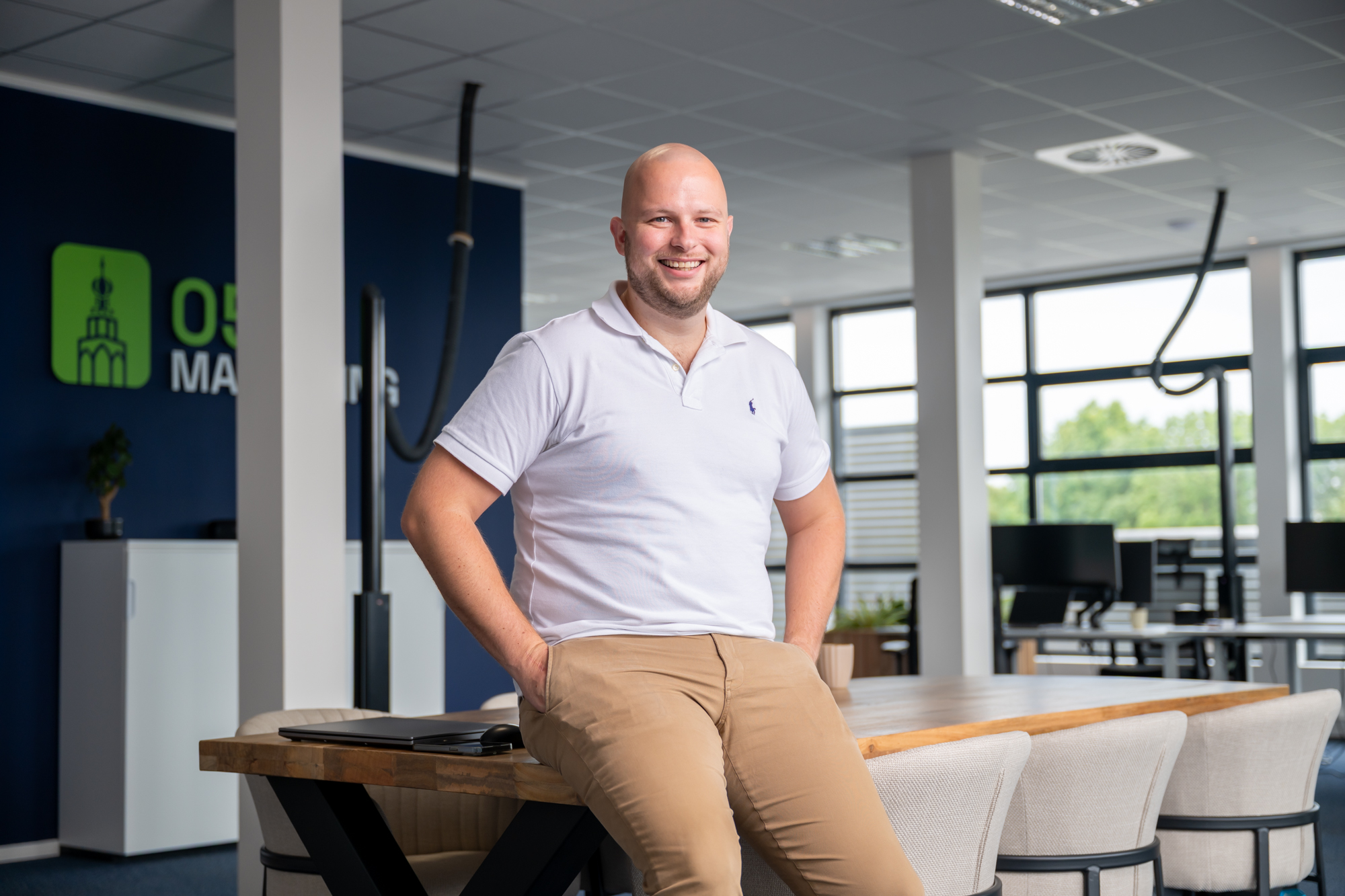 Tom zit lachend op de tafel bij 050 Marketing