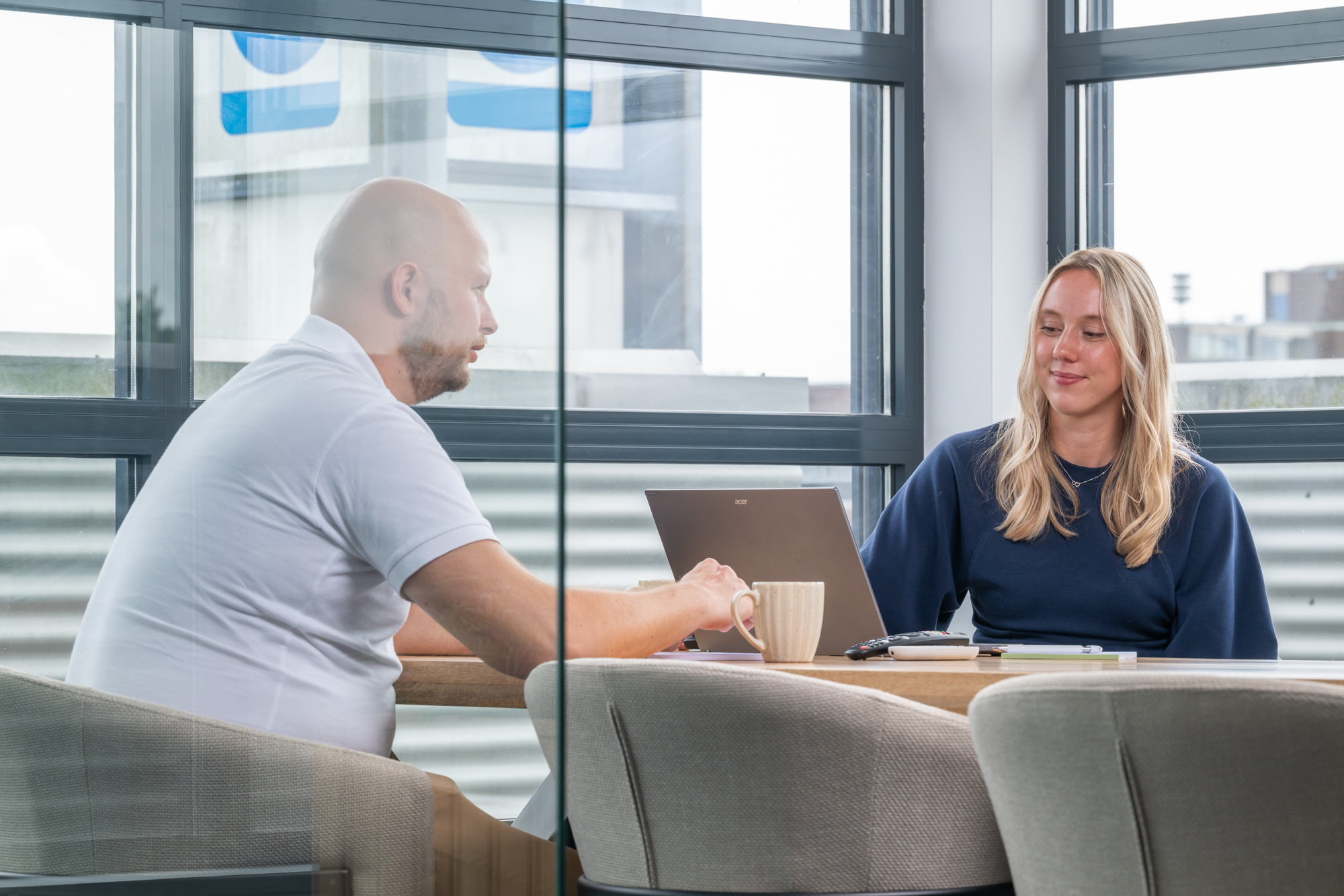 Tom en Sanne overleggen met koffie aan de vergadertafel